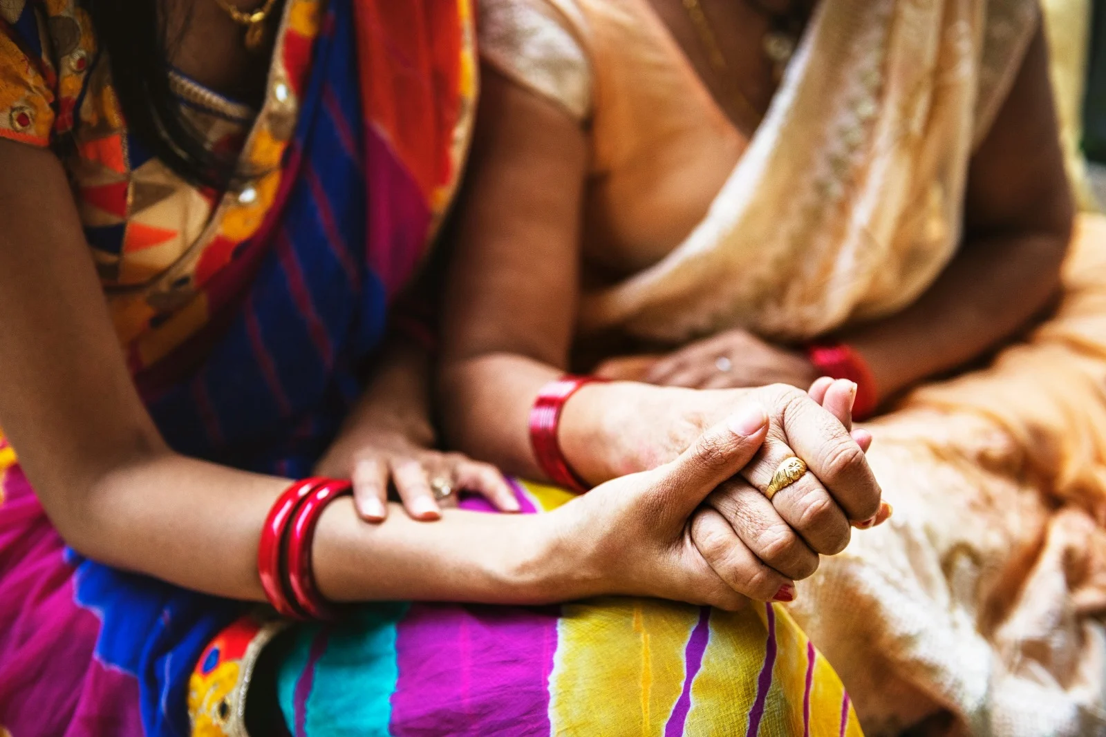 Two Indian women holding hands offering emotional support and care to overcome anxiety during menopause.