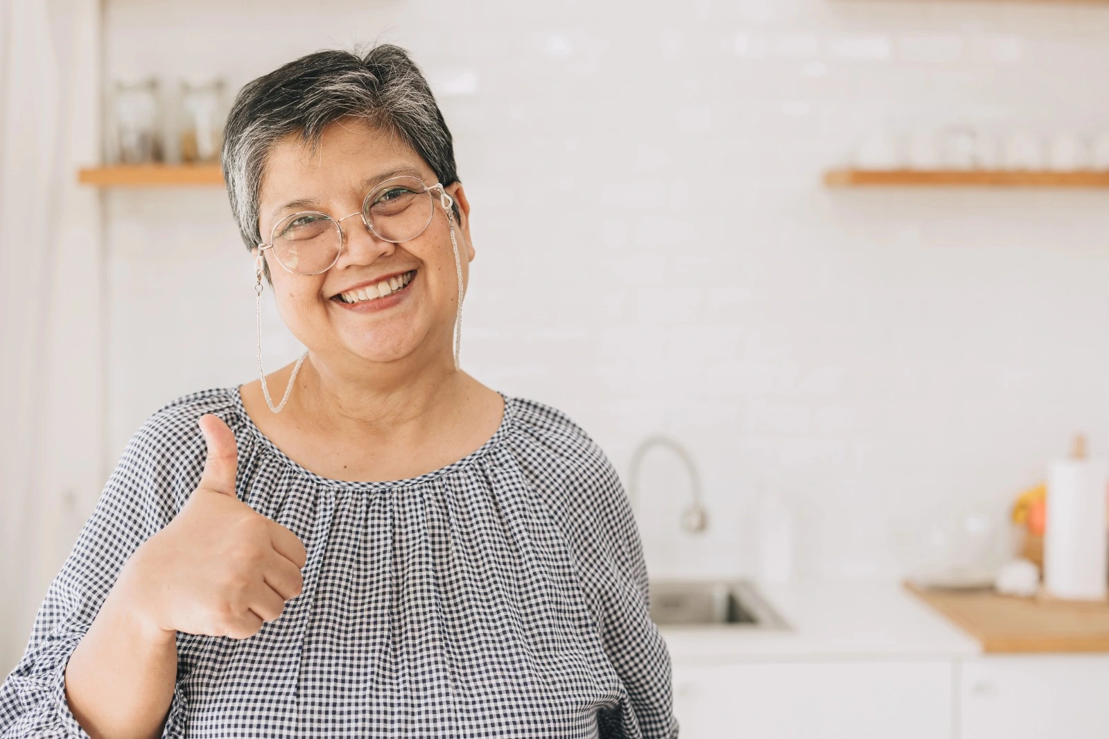 Smiling mature woman giving thumbs up at home, symbolizing healthy weight management and confidence during menopause.